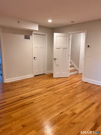 a view of an empty room with wooden floor and a window