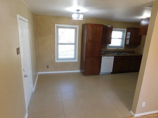 an empty room with windows and refrigerator