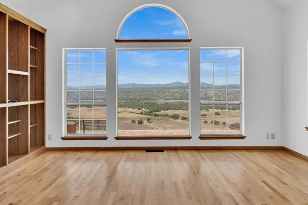a view of empty room with wooden floor and fan
