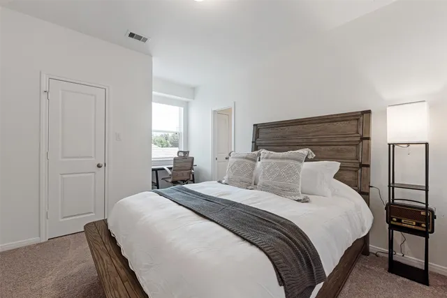 a bedroom with a bed and a lamp on dresser