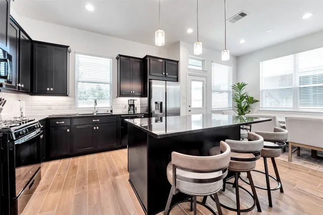 a kitchen with granite countertop a stove a sink dishwasher a dining table and chairs with wooden floor