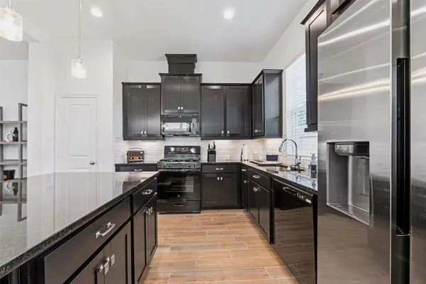 a kitchen with kitchen island granite countertop a sink appliances and cabinets