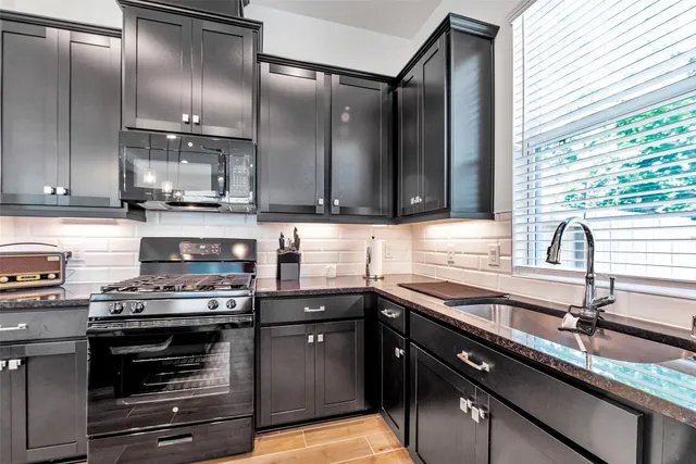 a kitchen with stainless steel appliances granite countertop a sink a stove and a refrigerator