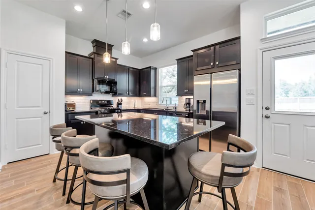 a kitchen with granite countertop kitchen island stainless steel appliances a dining table and chairs