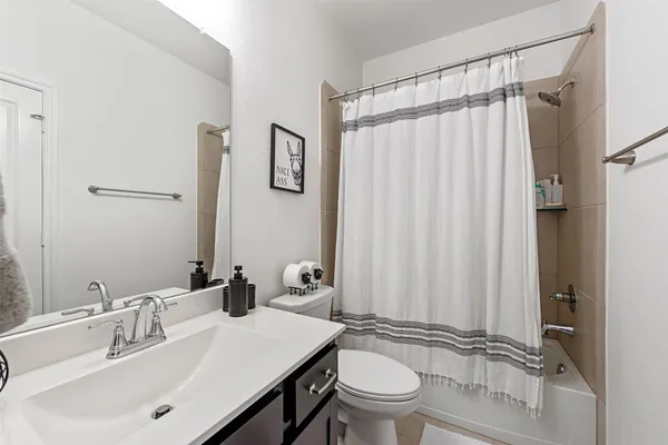 a bathroom with a sink a toilet a mirror and shower curtain
