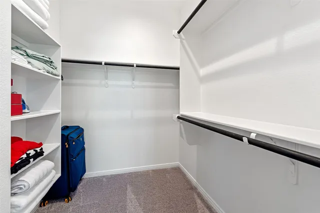 a view of walk in closet with clothes and shoes