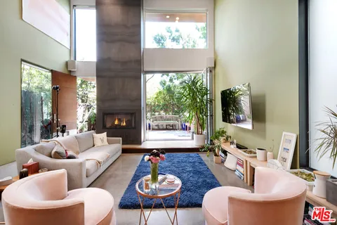 a living room with furniture a fireplace and a floor to ceiling window