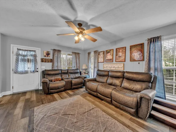 a living room with furniture a ceiling fan and a window