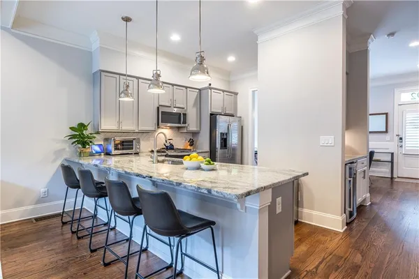 a room with stainless steel appliances kitchen island granite countertop furniture wooden floor and a view of kitchen