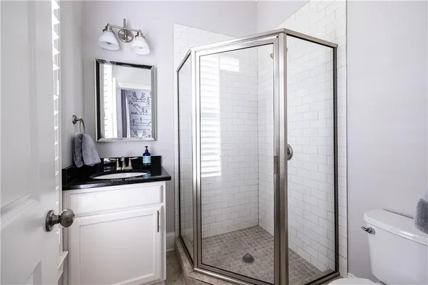 a bathroom with a granite countertop sink a mirror and a shower