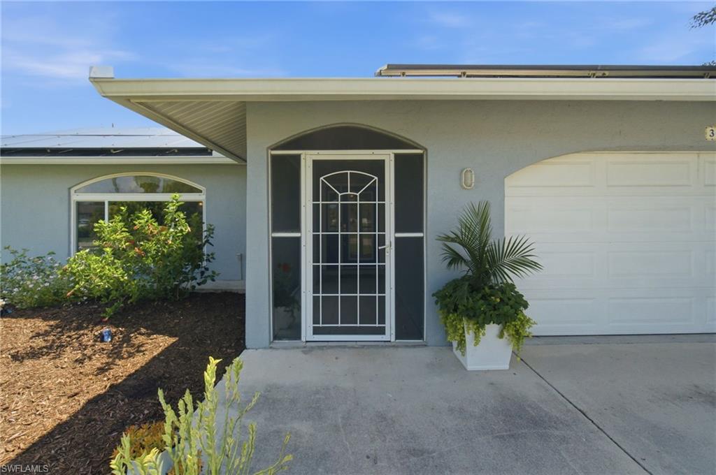 3022 47th Street Southwest Naples, FL 34116 - Photo 3 of 46 Front exterior with arched entry, screen door, and a two-car garage