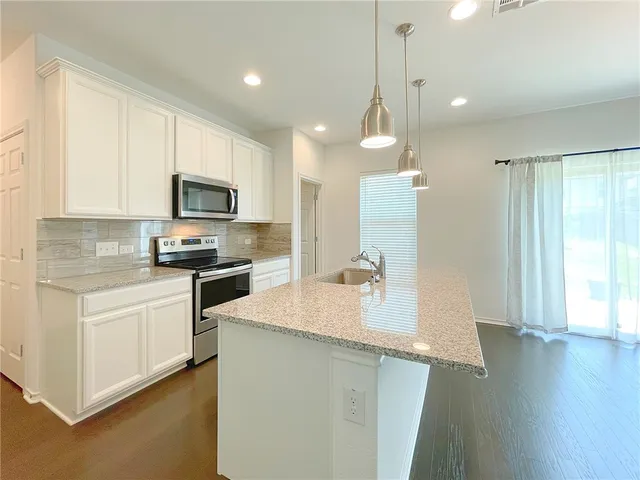 a kitchen with granite countertop a sink stainless steel appliances and cabinets