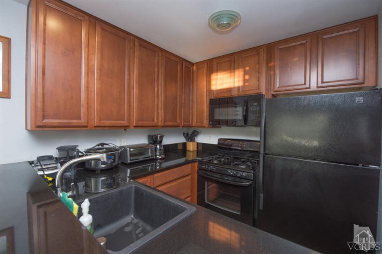 1718 Sinaloa Road, Unit 117 Simi Valley, CA 93065 - Photo 8 of 23 a kitchen with stainless steel appliances granite countertop a stove a sink dishwasher and cabinets with wooden floor