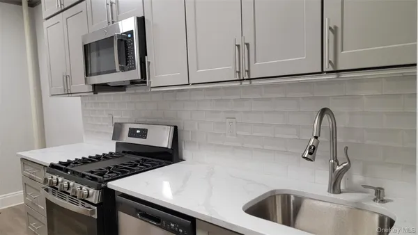 a kitchen with granite countertop a sink stove and cabinets