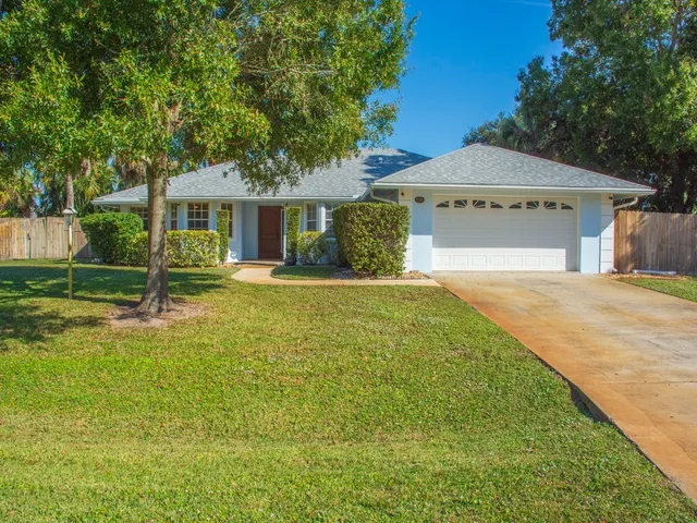 a view of a house with a yard and large tree