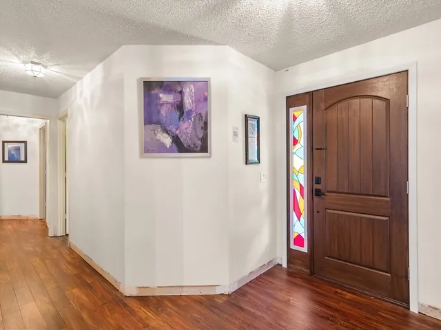 a view of a hallway with wooden floor and cabinets