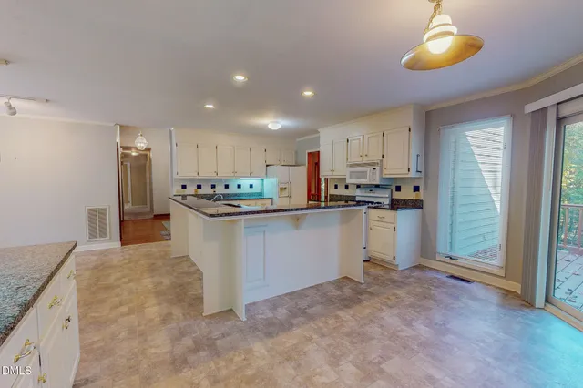 a kitchen that has a lot of white cabinets and stainless steel appliances