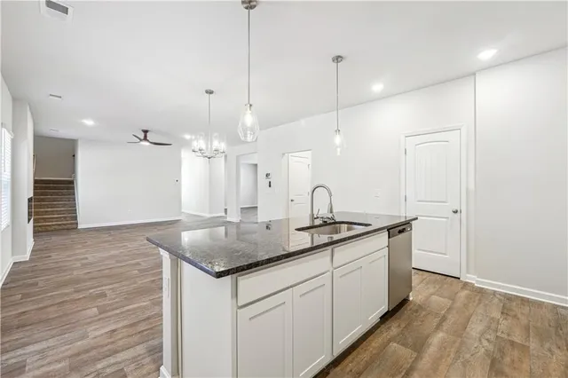 a kitchen with stainless steel appliances granite countertop a sink a refrigerator a large oven and white cabinets