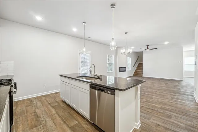 a kitchen with stainless steel appliances granite countertop a sink a counter space and wooden floor