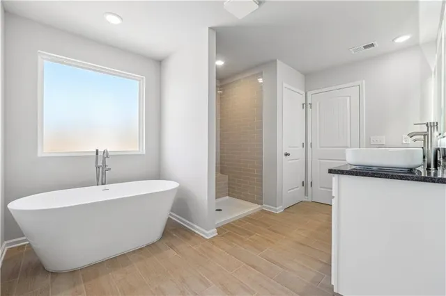 a spacious bathroom with a tub sink and mirror