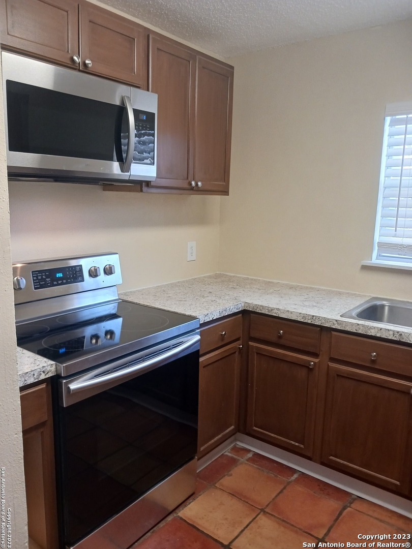 11725 Spring Ridge Drive San Antonio, TX 78249 - Photo 6 of 18 a kitchen with a sink stove and microwave