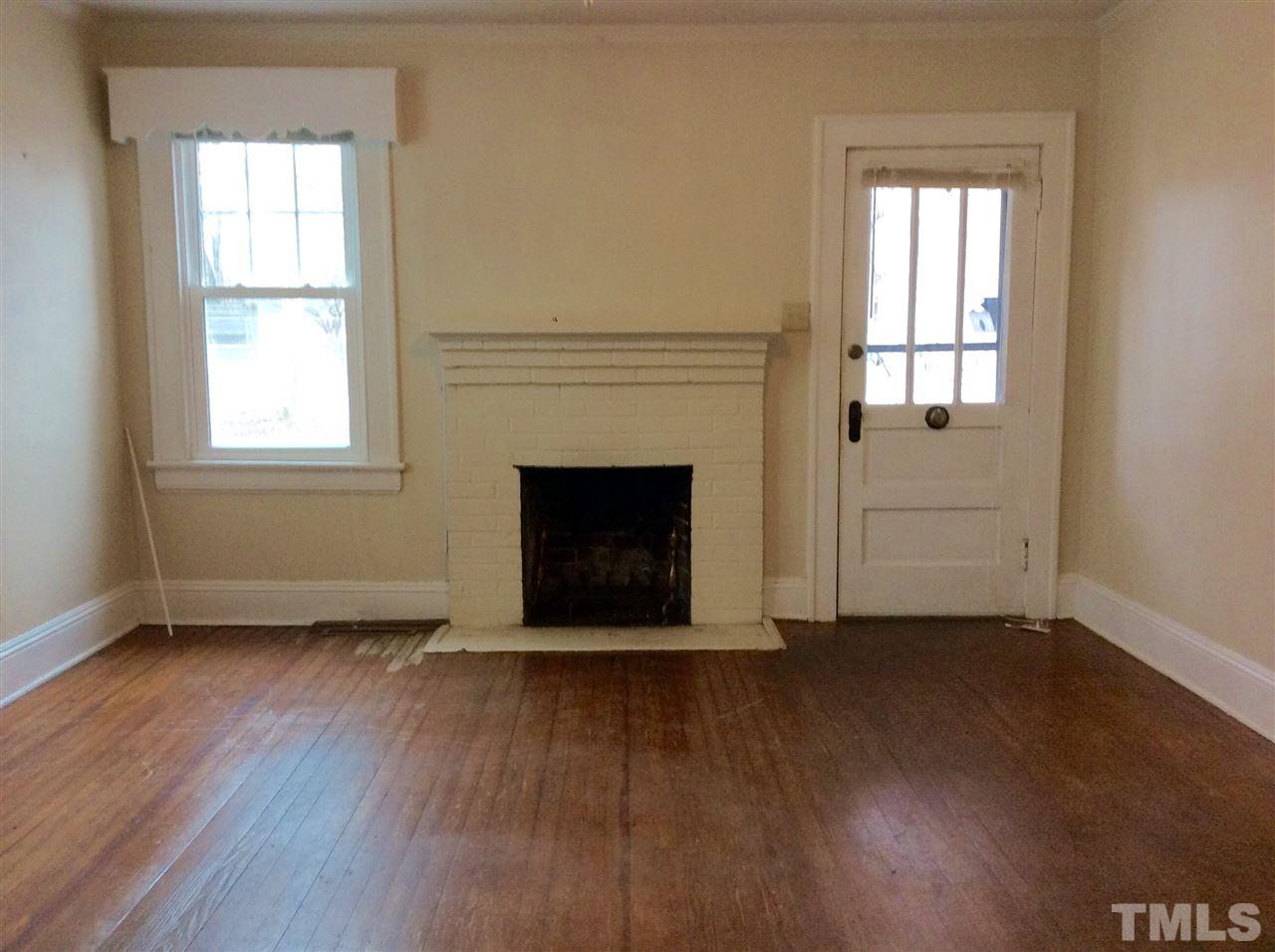 1309 Lake Wheeler Road Raleigh, NC 27603 - Photo 3 of 17 an empty room with wooden floor fireplace and windows