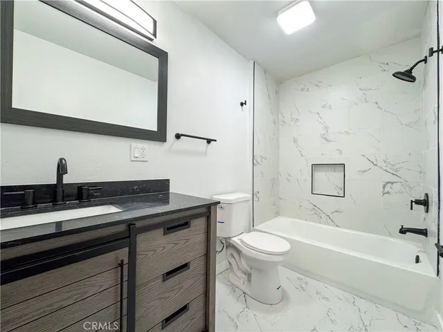 a bathroom with a granite countertop toilet sink and mirror