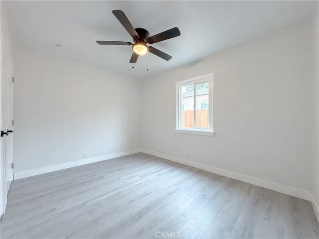an empty room with wooden floor fan and windows