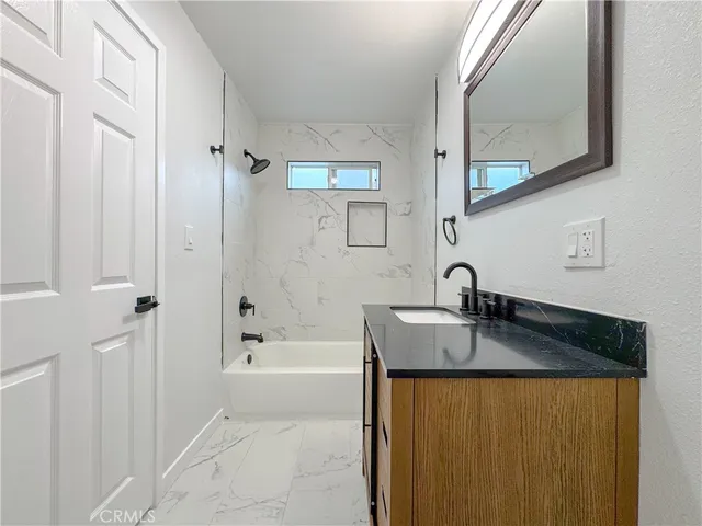 a bathroom with a granite countertop sink a mirror and a bathtub