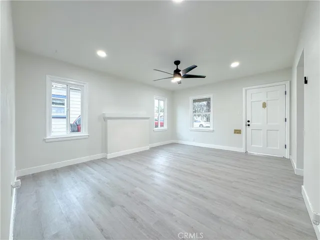 a view of an empty room with a window and wooden floor