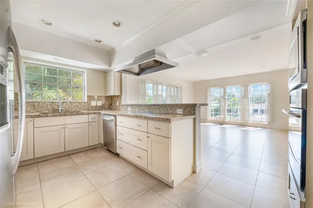 a kitchen with a stove a sink dishwasher and white cabinets with wooden floor