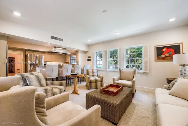 a living room with furniture kitchen view and a large window
