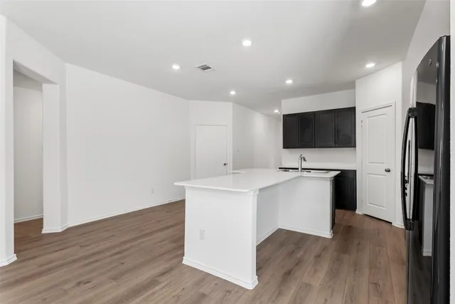 a kitchen with stainless steel appliances granite countertop a stove top oven a sink dishwasher and a refrigerator with wooden floor