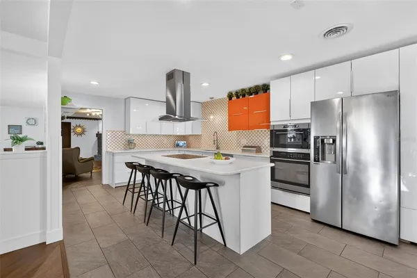 a kitchen with stainless steel appliances kitchen island granite countertop a refrigerator a stove and a sink with wooden floor