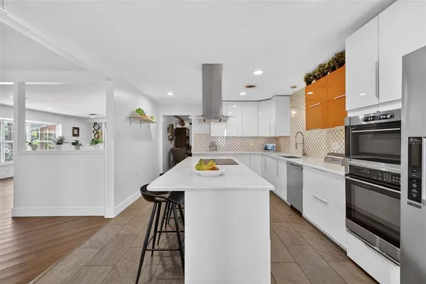 a kitchen with stainless steel appliances a stove a refrigerator a dining table and chairs with wooden floor