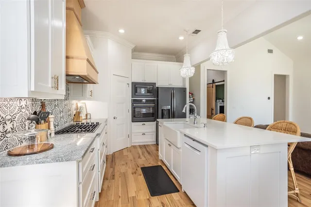 a kitchen with stainless steel appliances granite countertop a dining table chairs refrigerator and sink