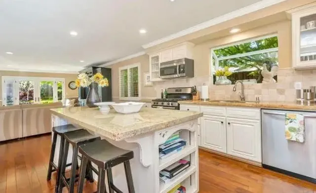 a kitchen with stainless steel appliances granite countertop a table chairs sink and cabinets