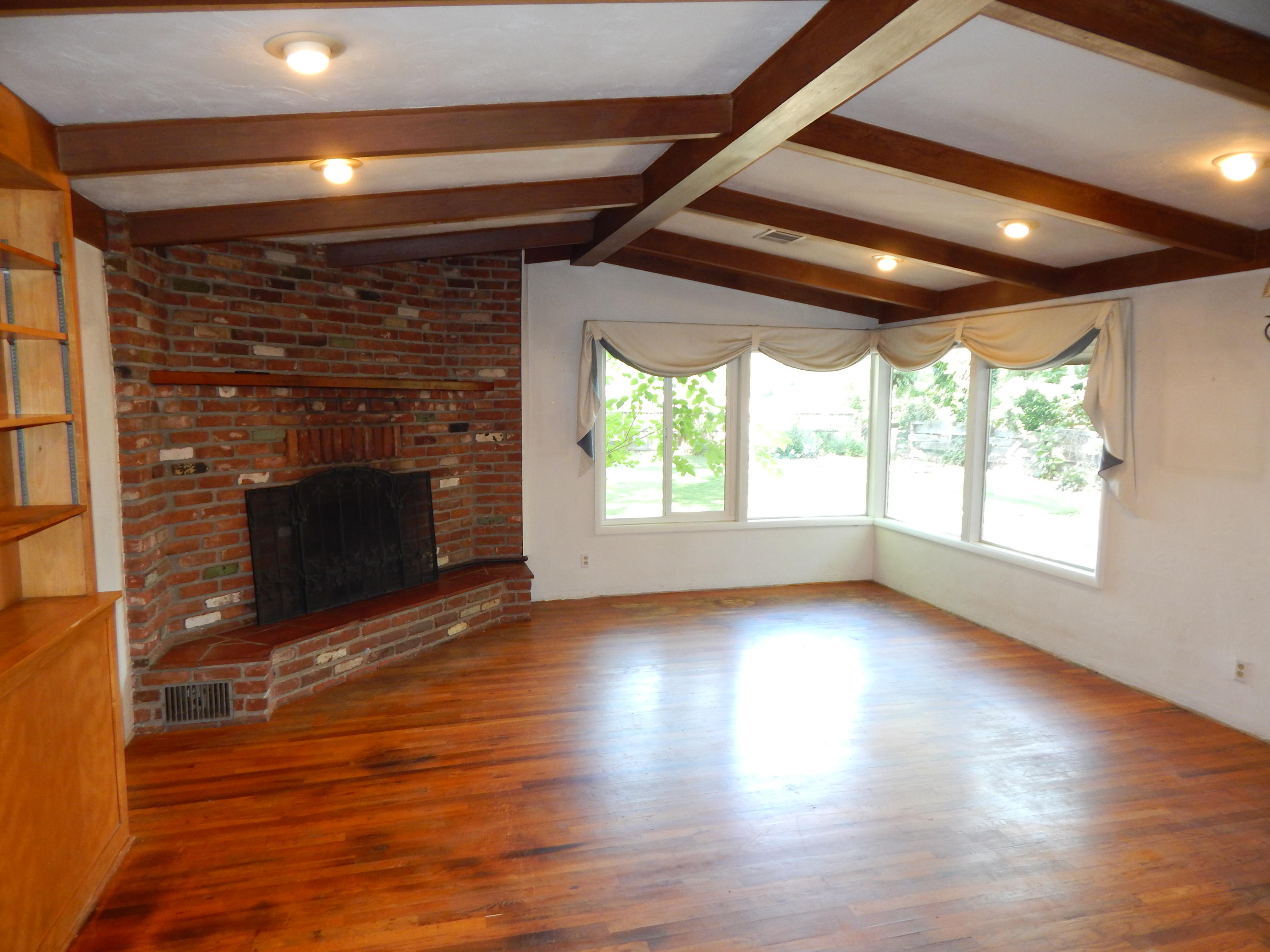 6460 Riverside Drive Redding, CA 96001 - Photo 6 of 81 an empty room with wooden floor fireplace and windows