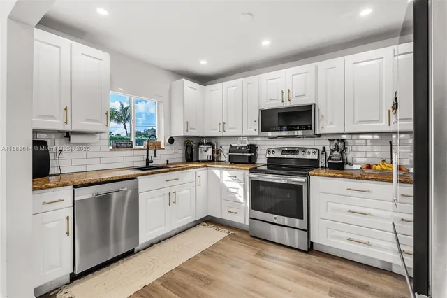 a kitchen with stainless steel appliances granite countertop a stove a sink and a microwave