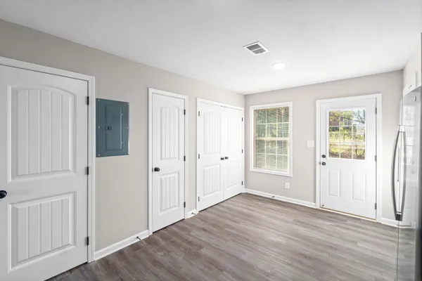 a view of an empty room with wooden floor and a window