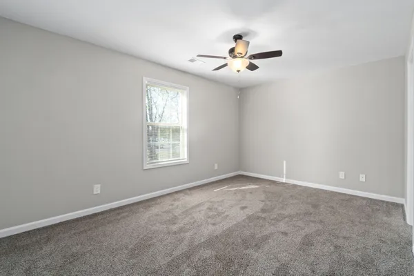 an empty room with windows and fan
