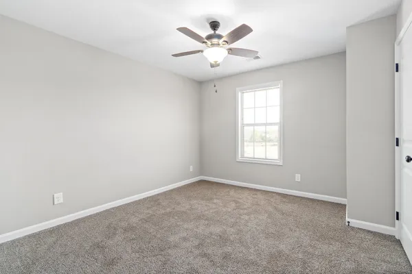 an empty room with windows and ceiling fan