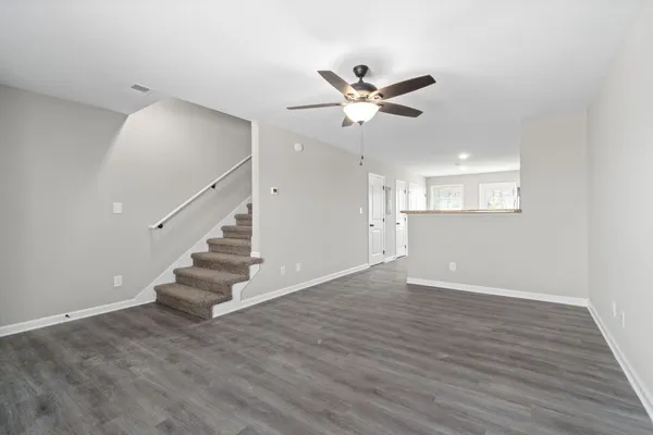 a view of an empty room with wooden floor and a ceiling fan