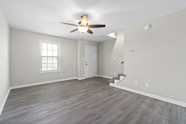 an empty room with wooden floor fan and windows