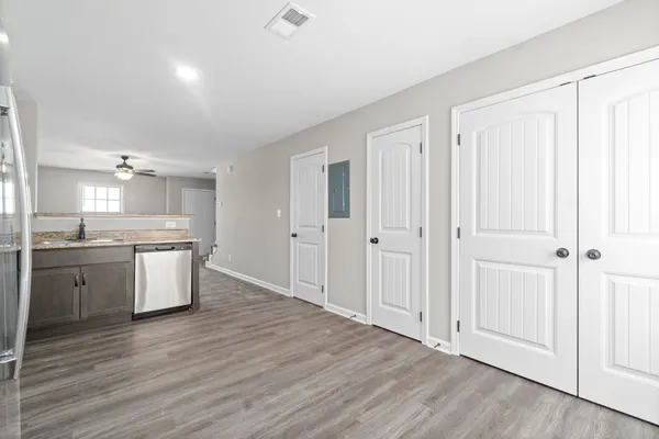 a room with kitchen island white cabinets and wooden floor