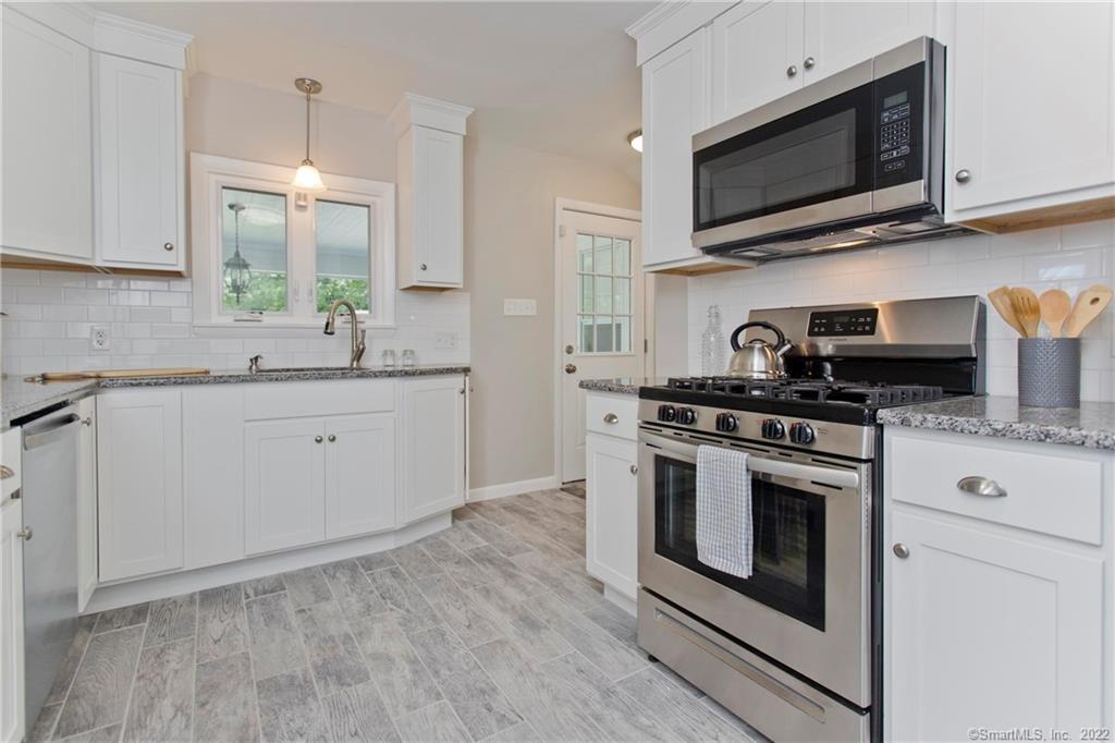 621 Plumtree Road Springfield, MA 01118 - Photo 1 of 1 a kitchen with stainless steel appliances granite countertop a sink a stove a microwave and wooden cabinets