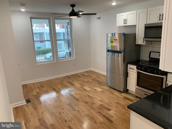 a view of a kitchen with wooden floor electronic appliances and window
