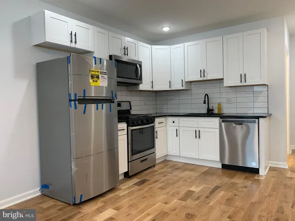 a kitchen with white cabinets stainless steel appliances and a sink