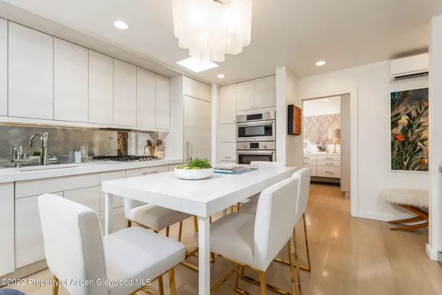 a kitchen with stainless steel appliances kitchen island granite countertop a table chairs and a refrigerator