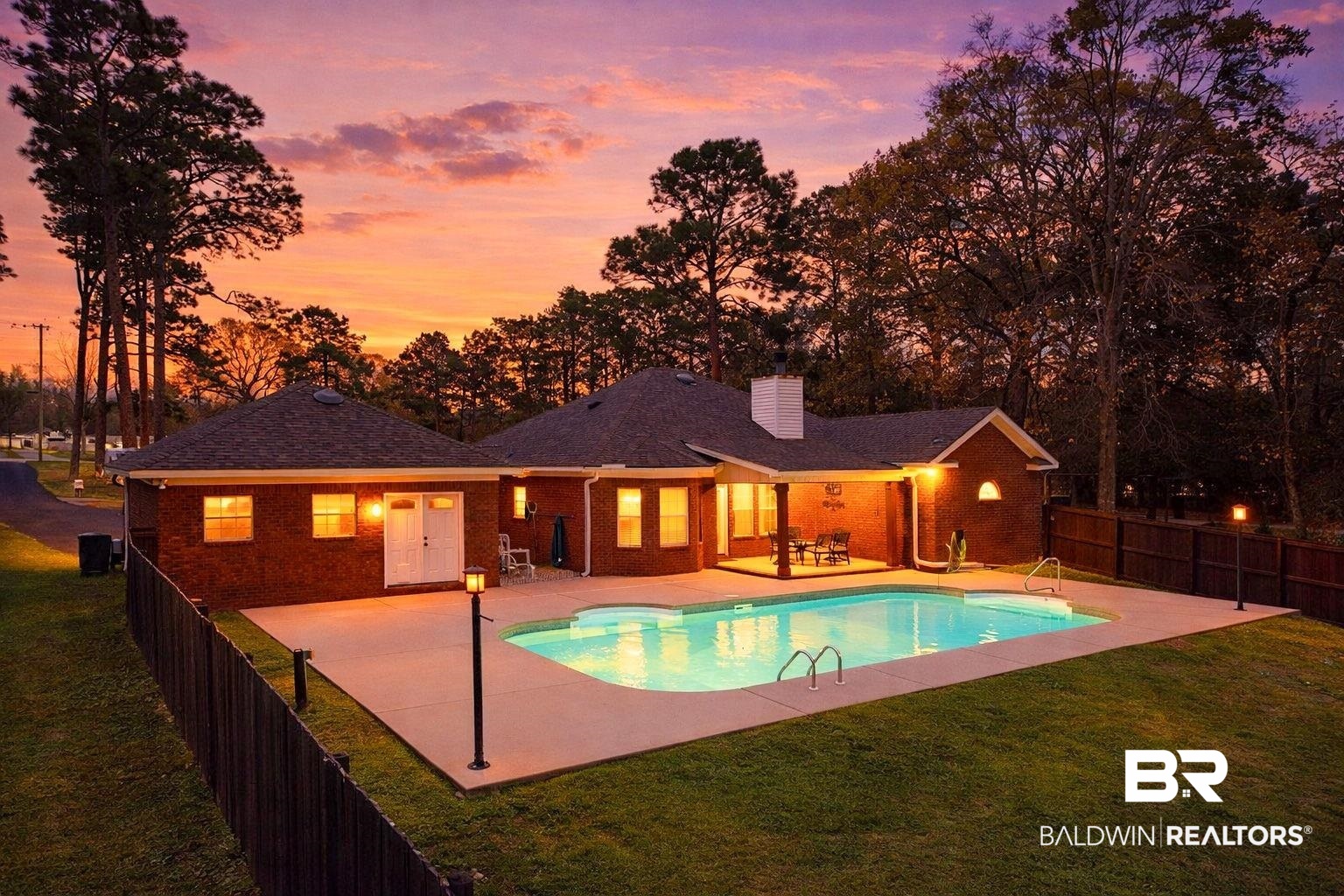 32185 Buzbee Road Daphne, AL 36527 - Photo 35 of 47 Back of property at dusk with a patio area, a fenced backyard, brick siding, and a chimney